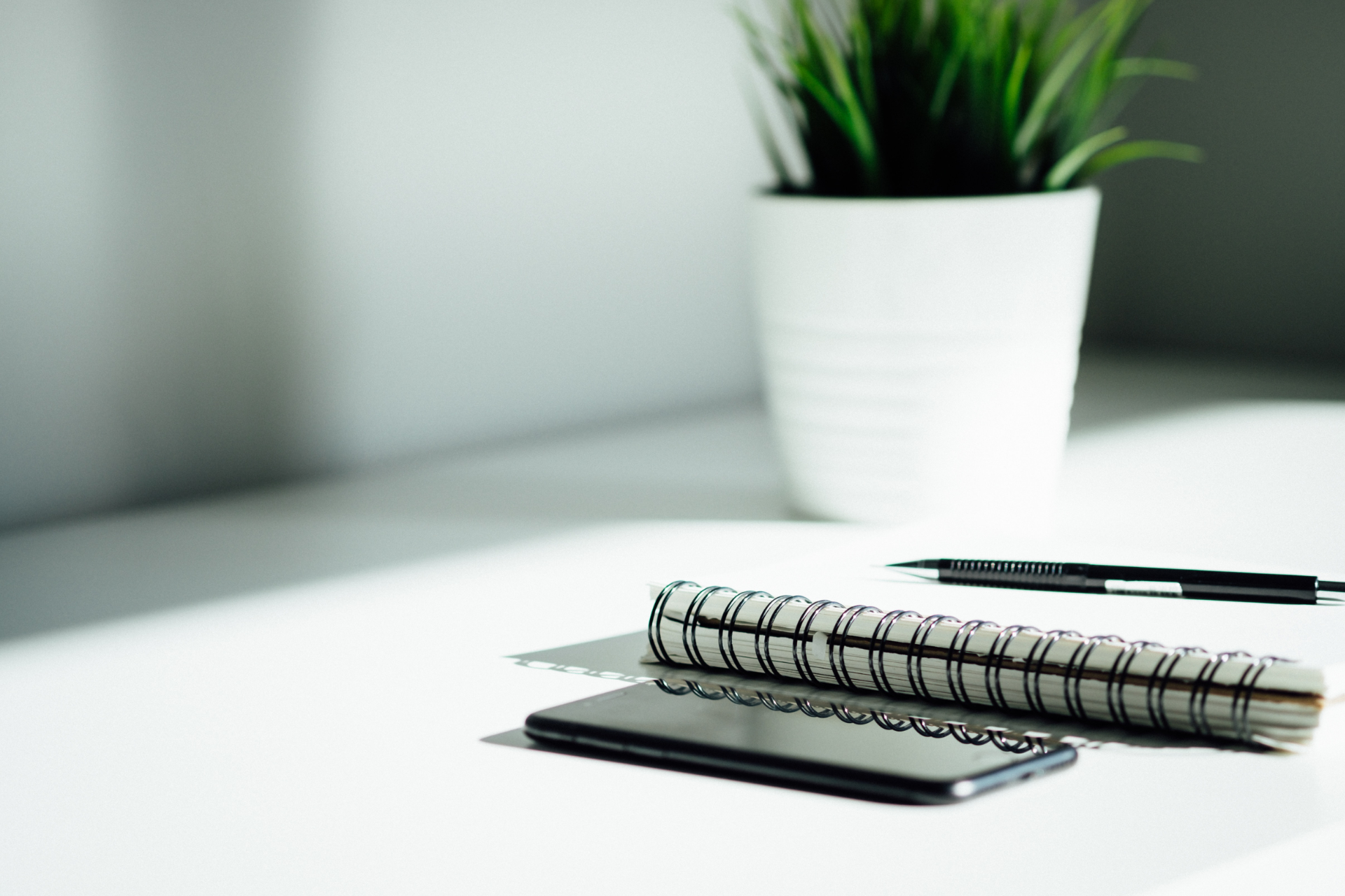 A phone next to a binder and a pen