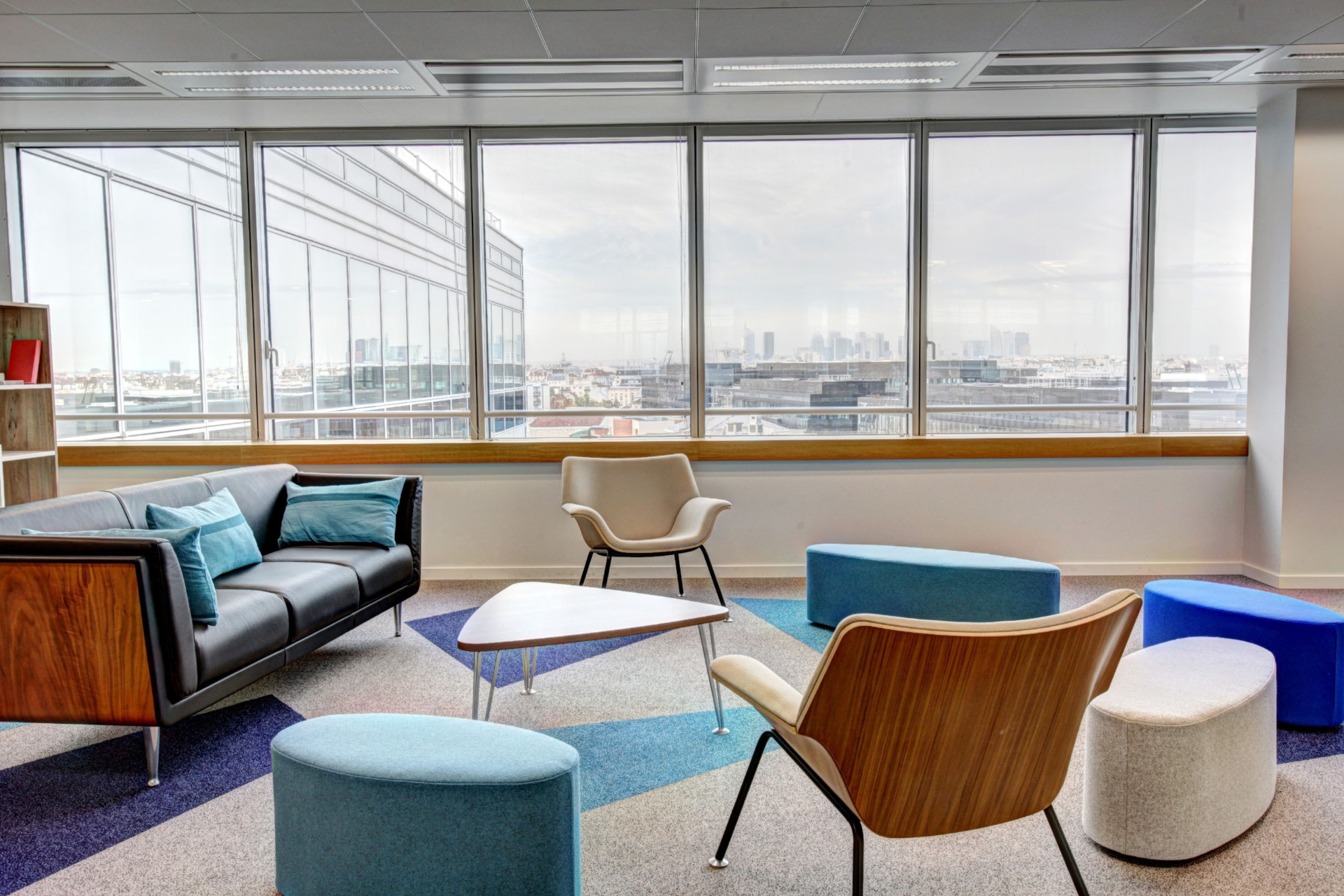 A room with some chairs, stools, settee and a triangular table.